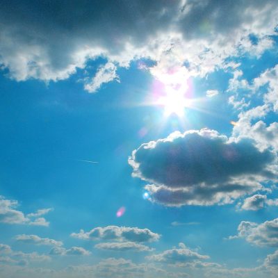 Sun on blue sky surrounded by clouds